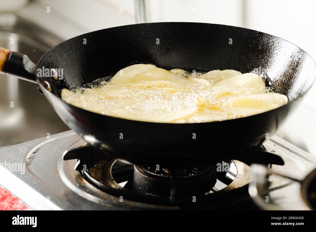 Le fette di patate vengono fritte in una padella. Foto Stock