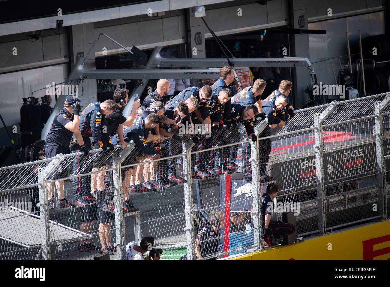 Red Bull pit crew in piedi sulle recinzioni del paddock, in attesa della vittoria di Max Verstappen al Gran Premio di Spagna. Foto Stock