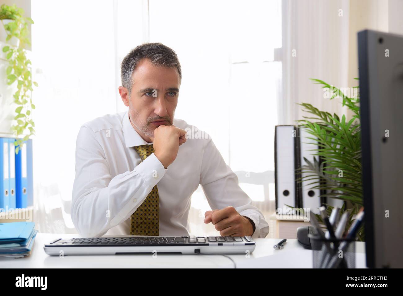Dettaglio di un uomo d'affari che lavora su un computer desktop che guarda lo schermo preoccupato in un ufficio Foto Stock