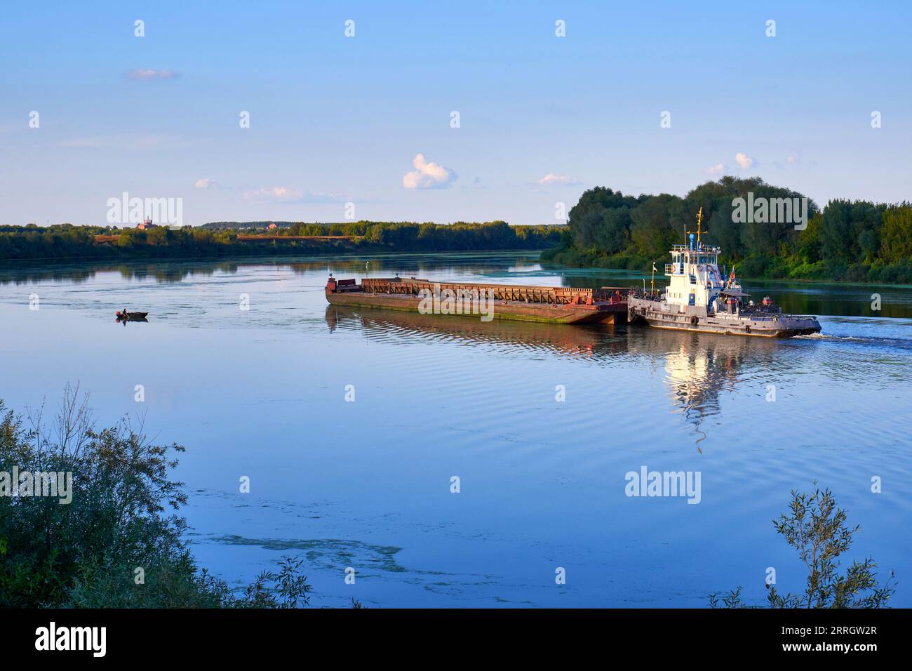 Un rimorchiatore con una chiatta galleggia lungo il fiume. Trasporto di merci via fiume Foto Stock