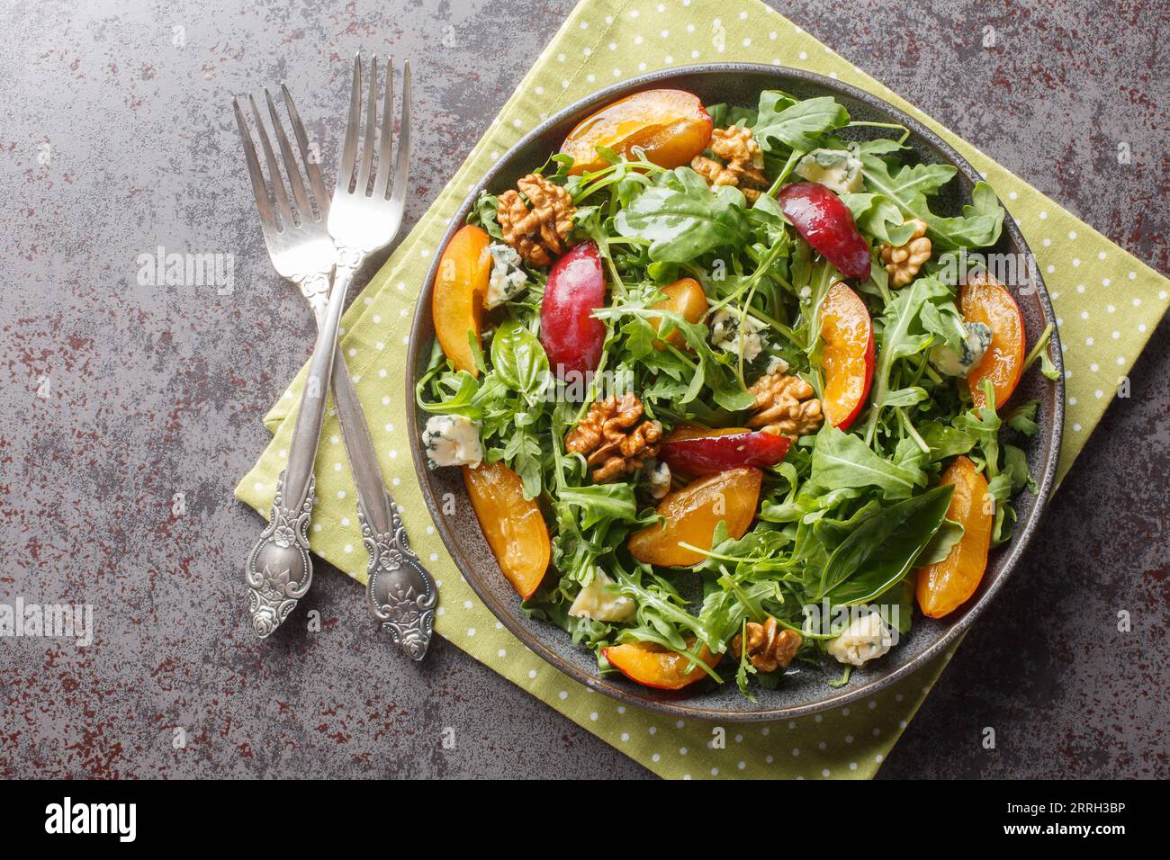 Insalata cruda con prugne, rucola, gorgonzola e noci da vicino in un piatto sul tavolo. vista superiore orizzontale dall'alto Foto Stock