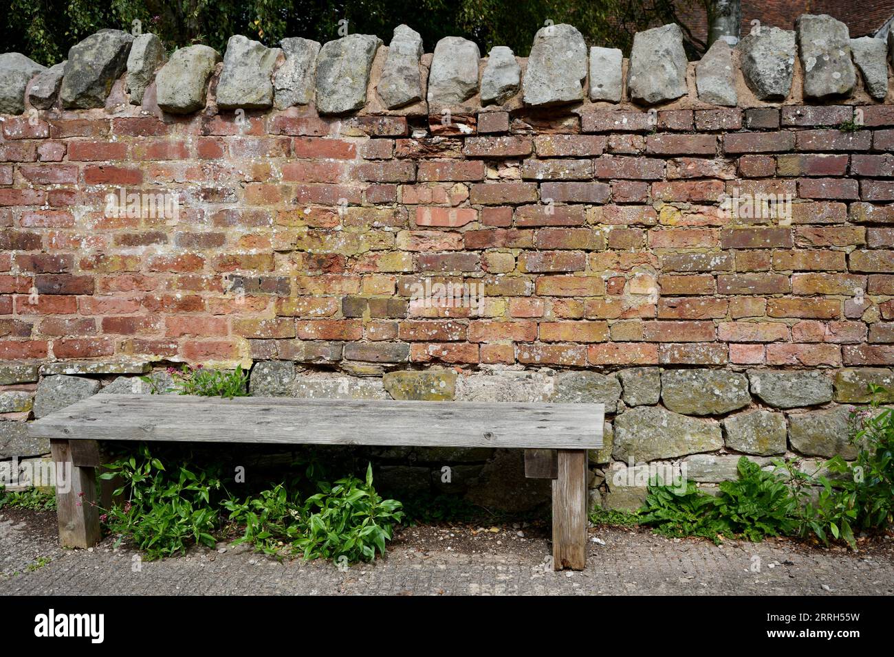 Panca rustica in legno di fronte ad una vecchia parete di mattoni. Foto Stock