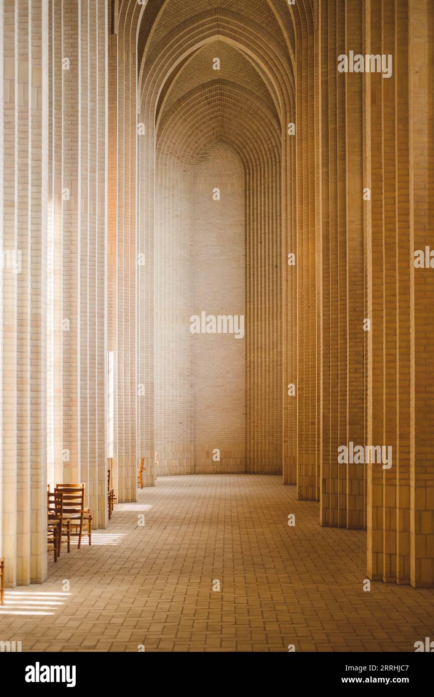 Tranquillo corridoio vuoto nella chiesa di Grundtvig con colonne altamente verticali e piastrelle di pietra Foto Stock