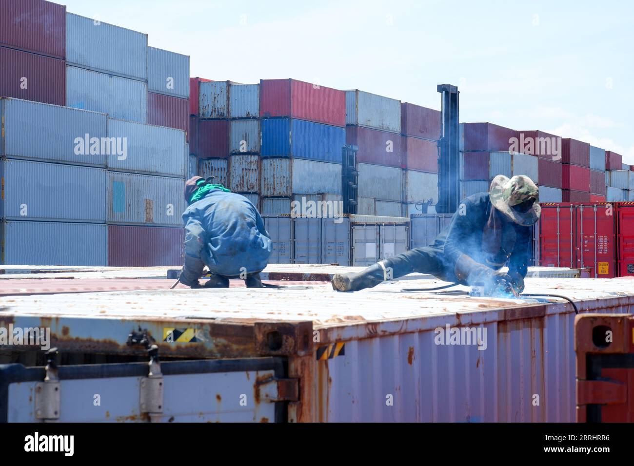 I lavoratori saldano a mano parti in acciaio e scatole per contenitori. Foto Stock