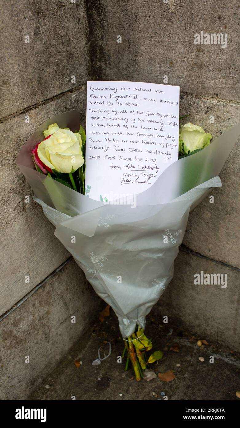 Londra, 8 settembre. 2023 il realista John Loughrey posa Flowers e una carta vicino al muro di Buckingham Palace per celebrare il primo anniversario della morte della regina Elisabetta II E siede sul verde accanto a Buckingham Palace con gli amici che accreditano Richard Lincoln/Alamy Live Foto Stock