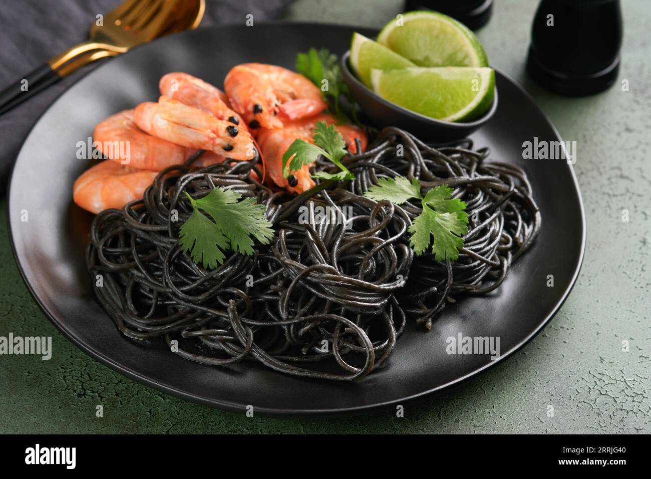 Spaghetti neri di gamberi su piatto nero su fondo scuro di cemento. Pasta con inchiostro calamaro e gamberi. Pasta a base di pesce. Vista dall'alto sulla linguetta in pietra verde Foto Stock