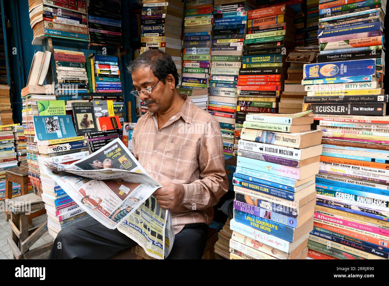 Venditore di libri all'interno della sua libreria in College Street a Calcutta, India Foto Stock