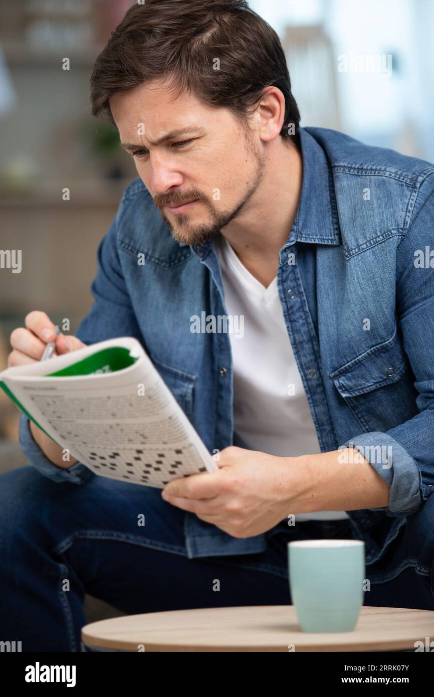 un uomo seduto a fare un puzzle con parole incrociate Foto Stock
