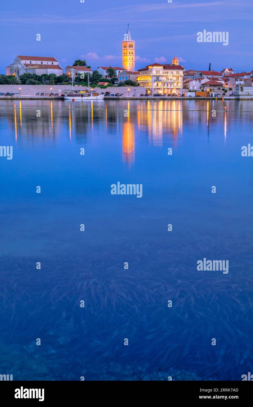 Europa, Croazia, Primorje-Gorski Kotar County, Rab Island, Rab, la città vecchia e gli edifici che si affacciano sul porticciolo al crepuscolo Foto Stock