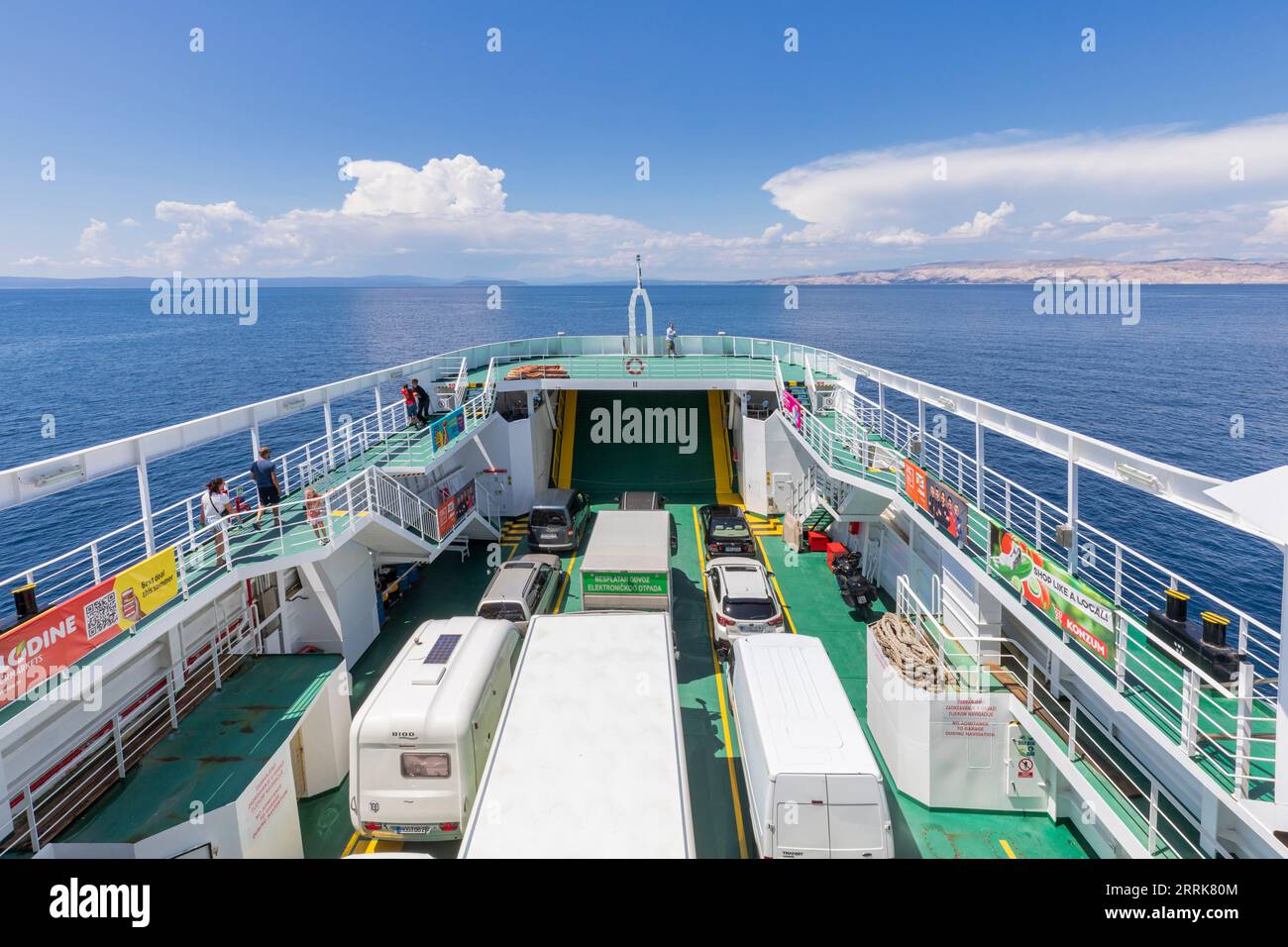 Croazia, baia del Quarnero, costa adriatica, traghetto da Lopar (Isola di Arbe) a Valbiska (Isola di Krk), vista dal traghetto con auto parcheggiate e passeggeri sul ponte Foto Stock