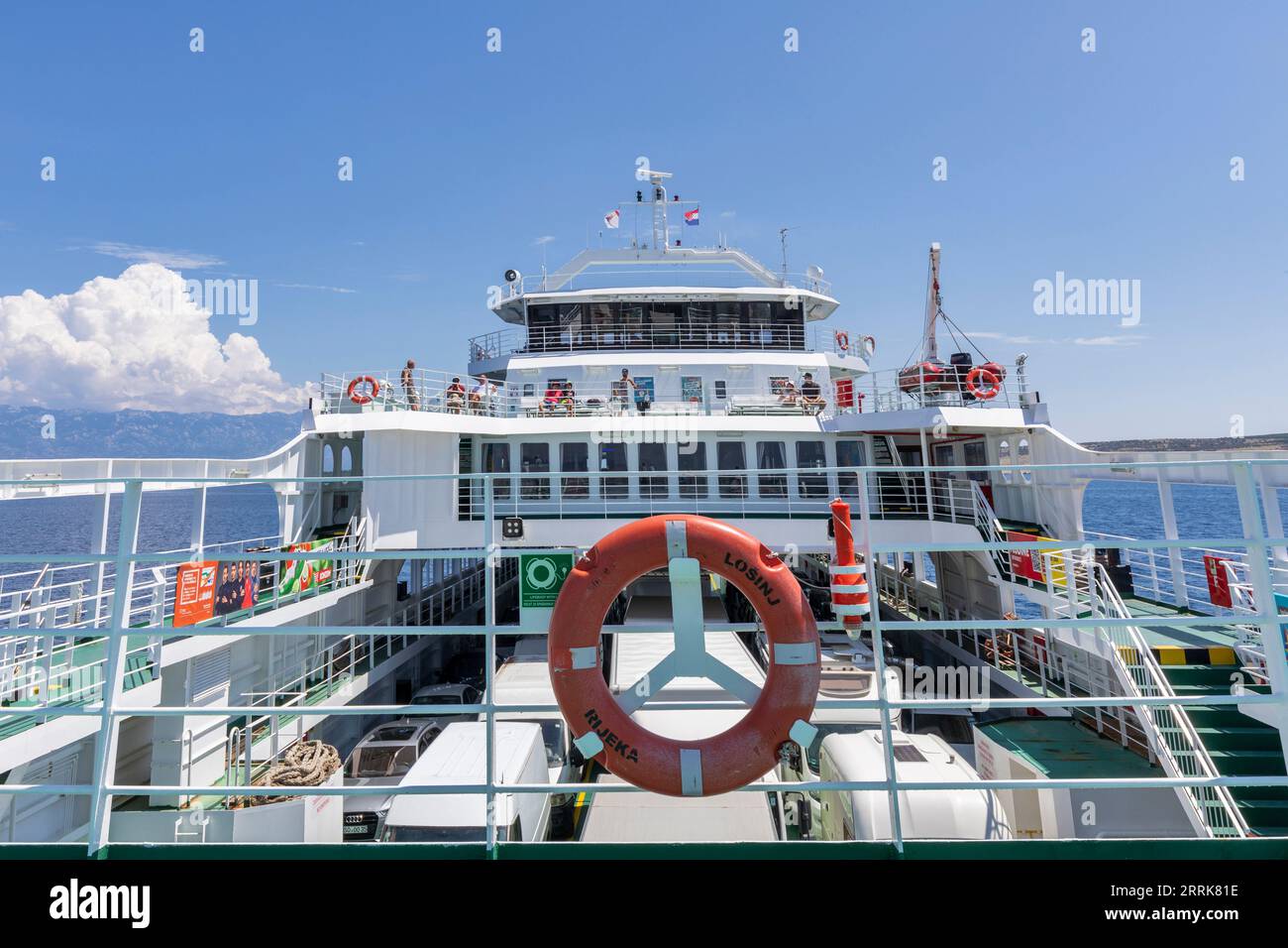 Croazia, baia del Quarnero, costa adriatica, traghetto da Lopar (Isola di Arbe) a Valbiska (Isola di Krk), vista dal traghetto con auto parcheggiate e passeggeri sul ponte Foto Stock