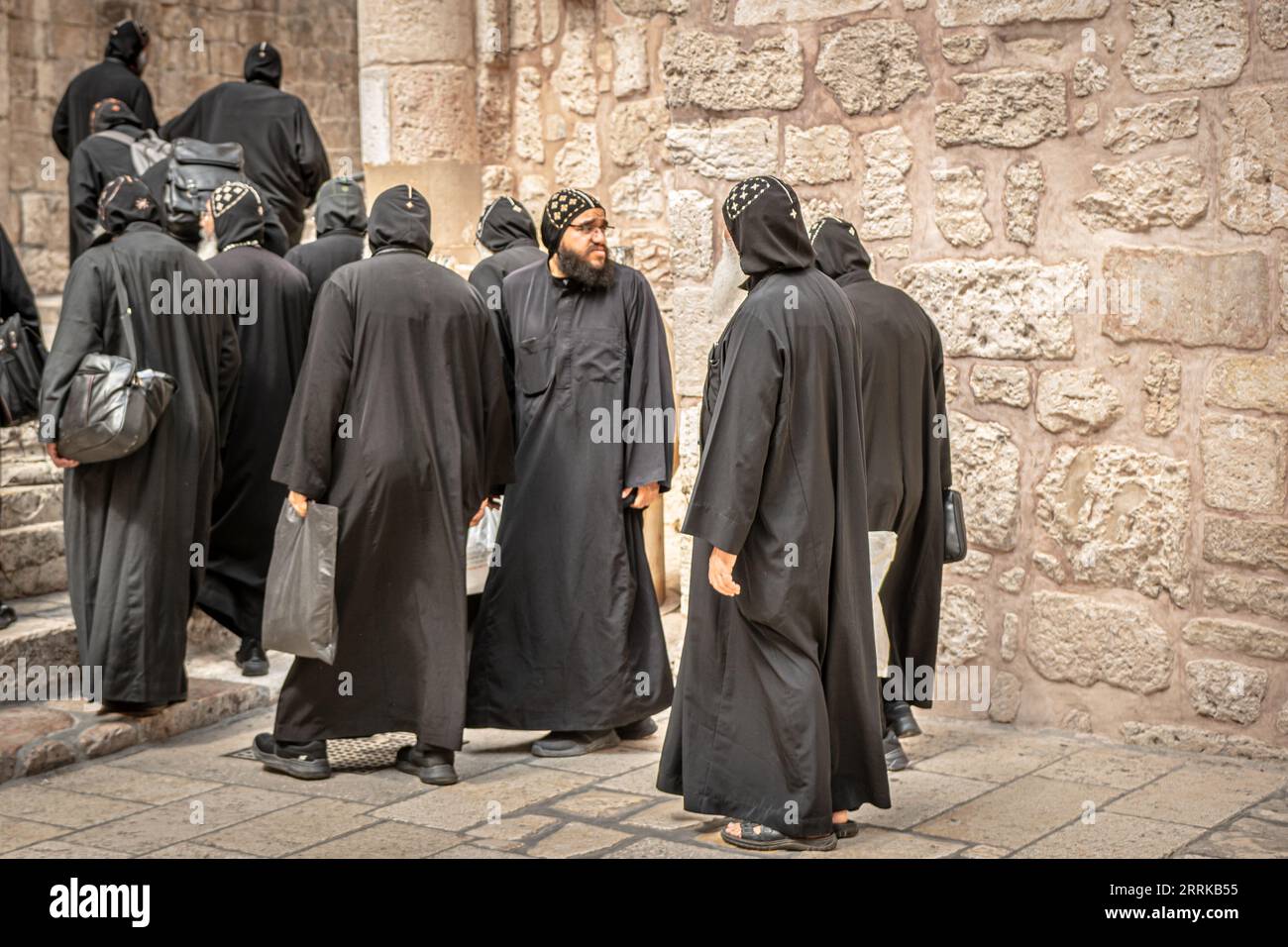 Un gruppo di uomini che indossano abaya sta in fila all'esterno con le mani legate insieme Foto Stock