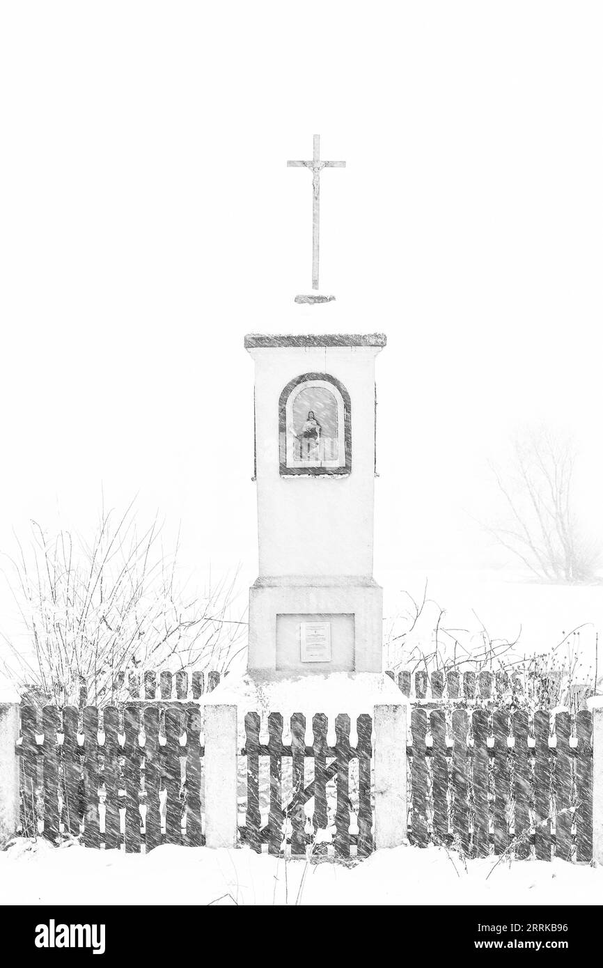 Antico santuario lungo il tragitto in campagna, in mezzo a campi di neve in inverno Foto Stock