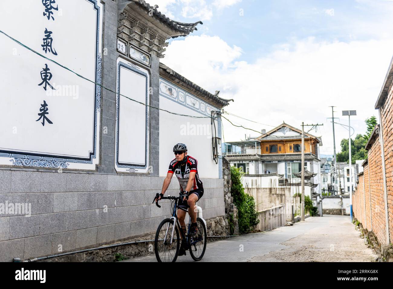 220908 -- DALI, 8 settembre 2022 -- Jos Van der Wiel Cycles in a Village of Dali, South West China S Yunnan Province, 29 agosto 2022. Sono passati più di 40 anni da quando Jos Van der Wiel è arrivato in Cina dai Paesi Bassi. Nel corso dei decenni, l'olandese si è appassionato di organizzare turisti in tutto il mondo per viaggiare in Cina in bicicletta. Durante i suoi tour in bicicletta, Jos ha conosciuto bene la Cina. Ha anche compilato una guida di viaggio in Cina, offrendo una guida completa ai lettori olandesi. Nel 2000, mentre Jos esplorava nuovi percorsi per tour in bicicletta nella provincia dello Yunnan della Cina sud-occidentale, incontrò la sua attuale moglie Huang J Foto Stock