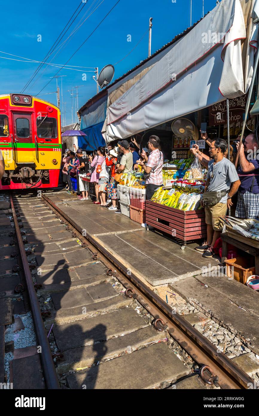 Il treno passa attraverso le bancarelle, vende cibo su rotaie, il mercato ferroviario di Maeklong, il mercato ferroviario di Talad Rom Hub, vicino a Bangkok, Samut Songkhram, Thailandia, Asia Foto Stock