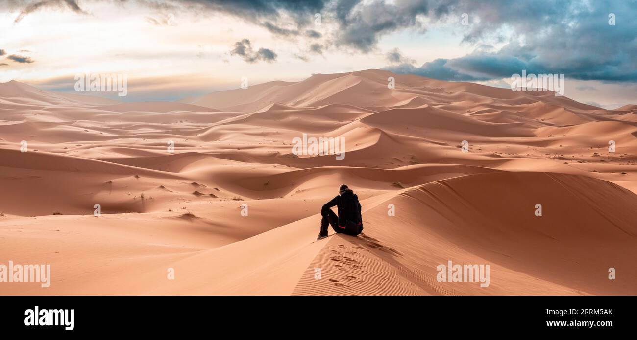 Una persona seduta nel deserto di Erg Chebbi nel Sahara africano, in Marocco Foto Stock