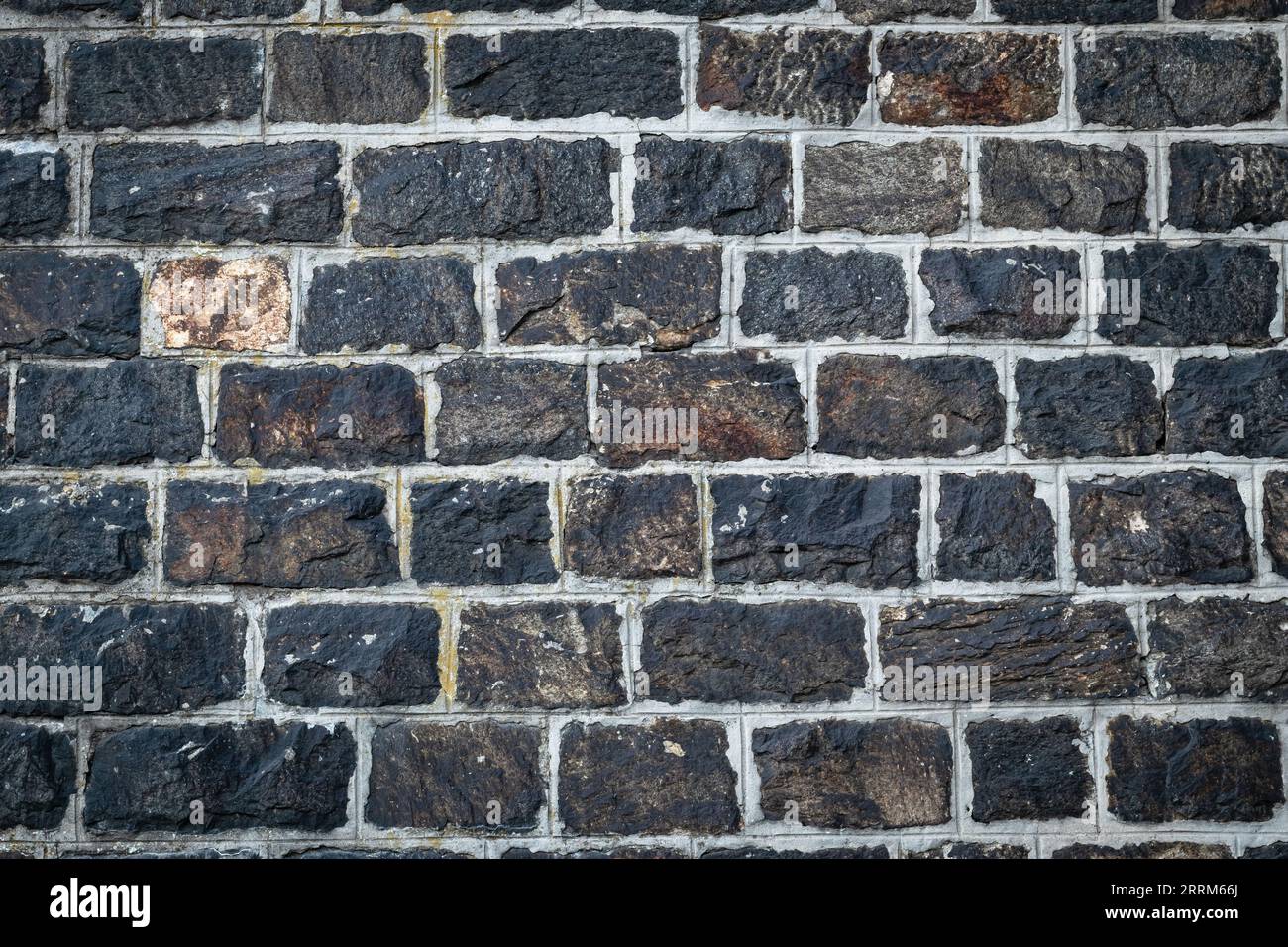 Sfondo murale in pietra scura. Vecchia struttura in mattoni neri, pavimento in roccia. Materiale da costruzione naturale, granito vintage, superficie grunge, esterno ruvido Foto Stock