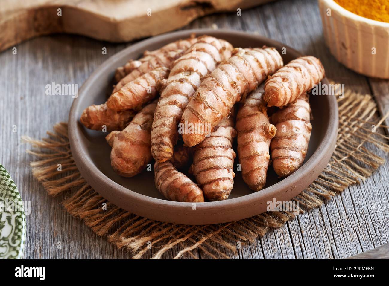 Radice di curcuma fresca su un tavolo con polvere di curcuma essiccata sullo sfondo Foto Stock