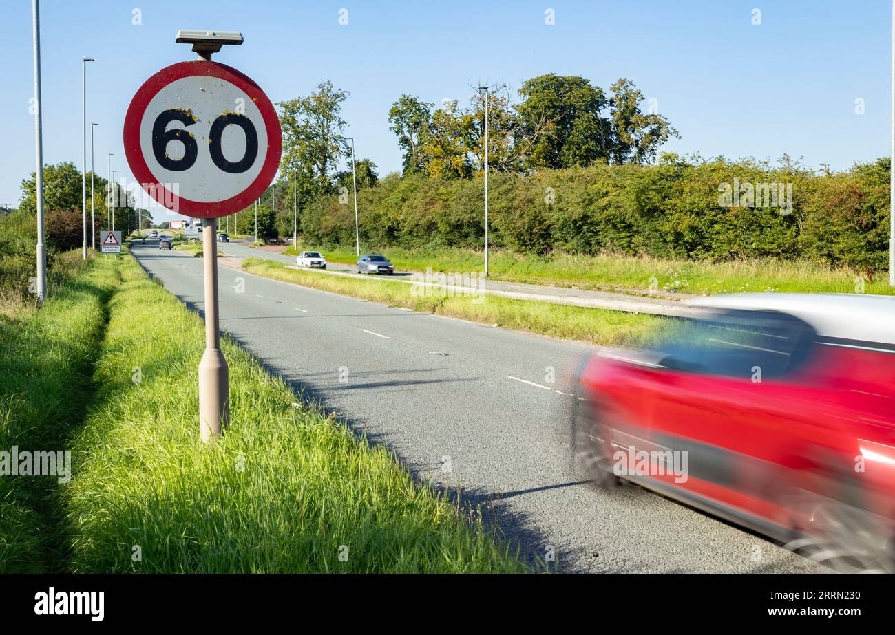 Segnale del limite di velocità con l'auto che passa in movimento sfocata Foto Stock