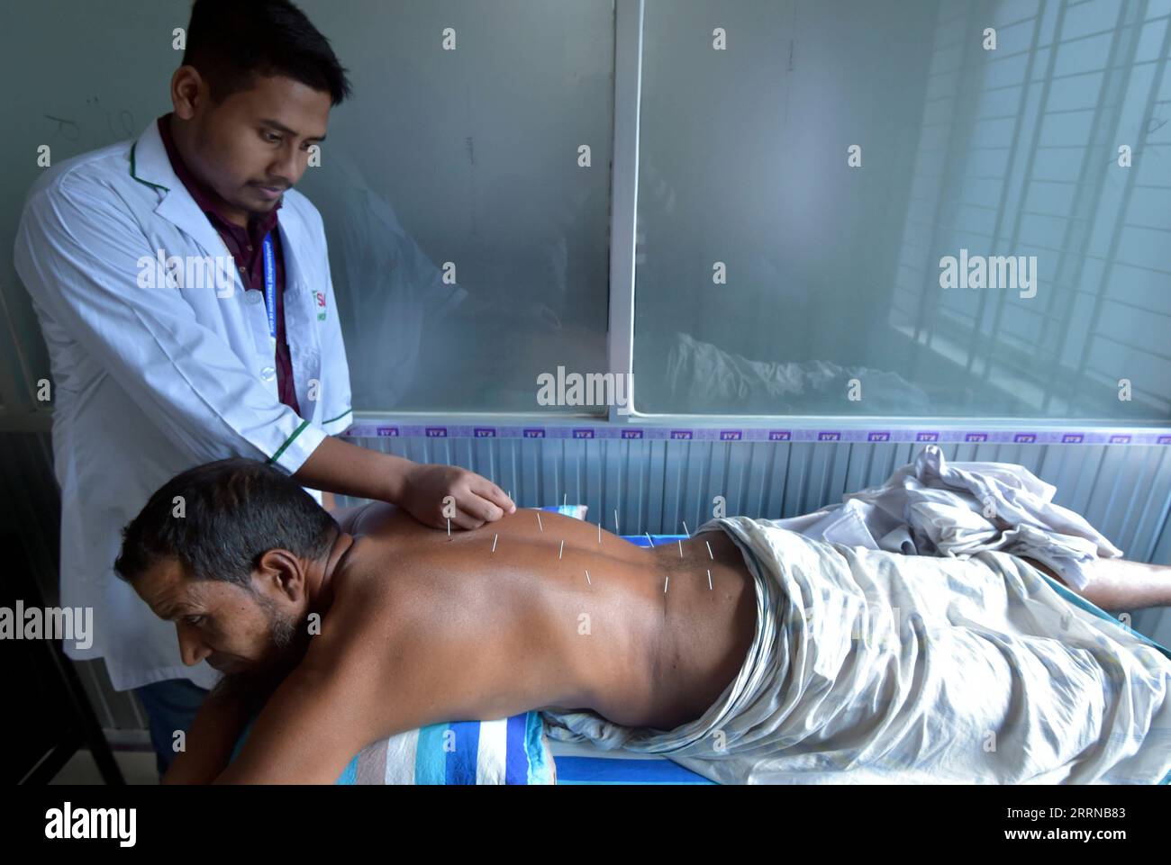 230101 -- MADARIPUR, 1 gennaio 2023 -- Un operatore medico effettua agopuntura per curare un paziente durante un campo medico gratuito a Madaripur, Bangladesh, il 23 dicembre 2022. PER ANDARE CON la caratteristica: La medicina tradizionale cinese raggiunge la campagna del Bangladesh con i benestanti BANGLADESH-MADARIPUR-MEDICINA TRADIZIONALE CINESE Salim PUBLICATIONxNOTxINxCHN Foto Stock