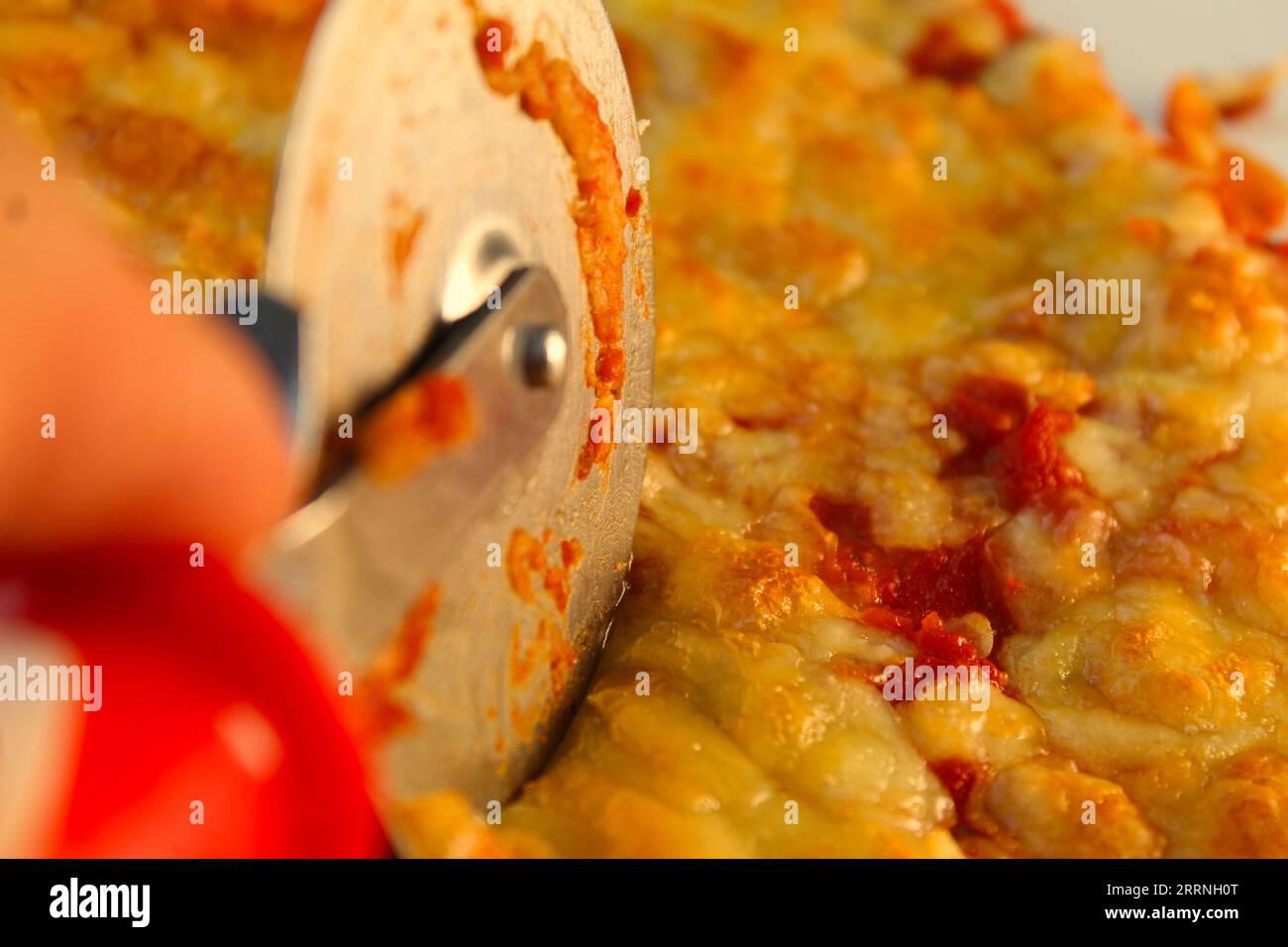 Una foto di alcuni che tagliano una pizza alla margerita con un taglialegna. Foto Stock