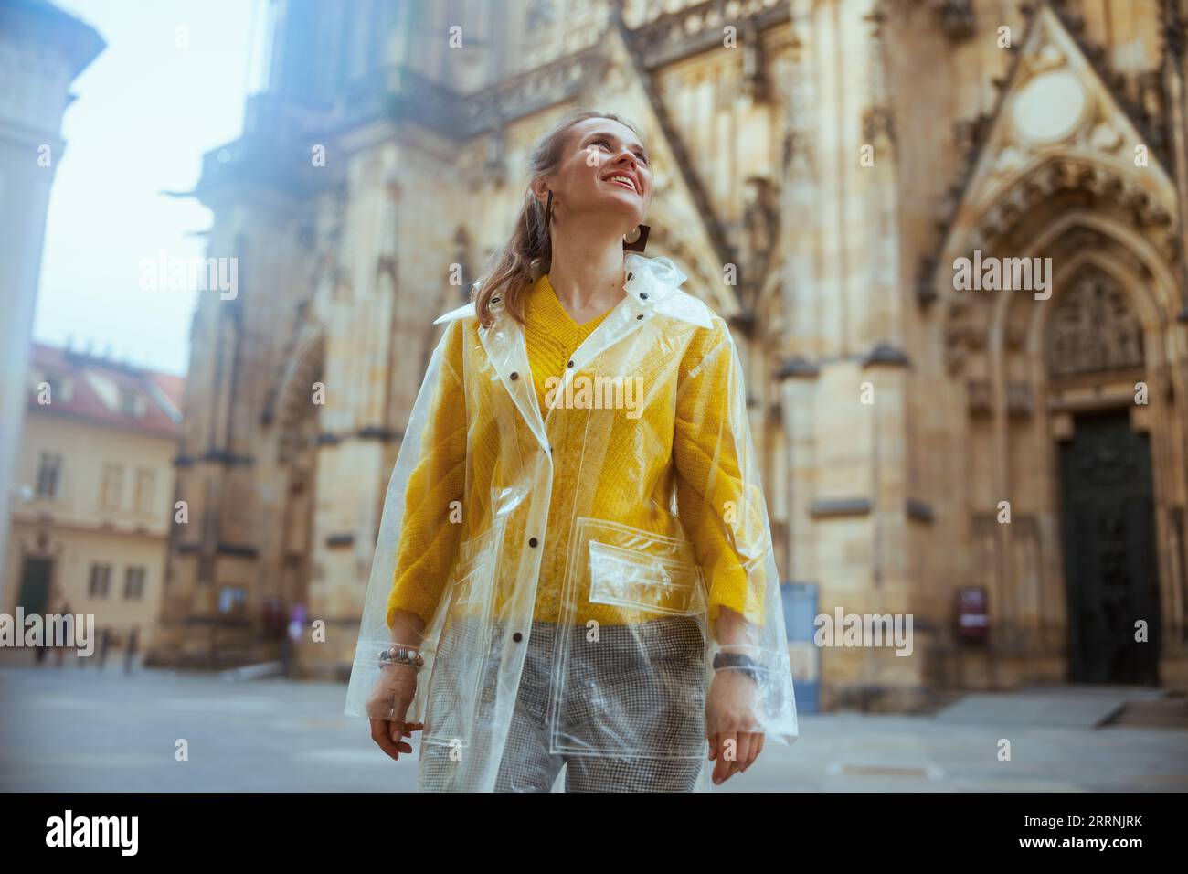 Tour a piedi di Praga, in una camicetta gialla e un impermeabile, sorpreso da una donna viaggiatrice moderna. Foto Stock