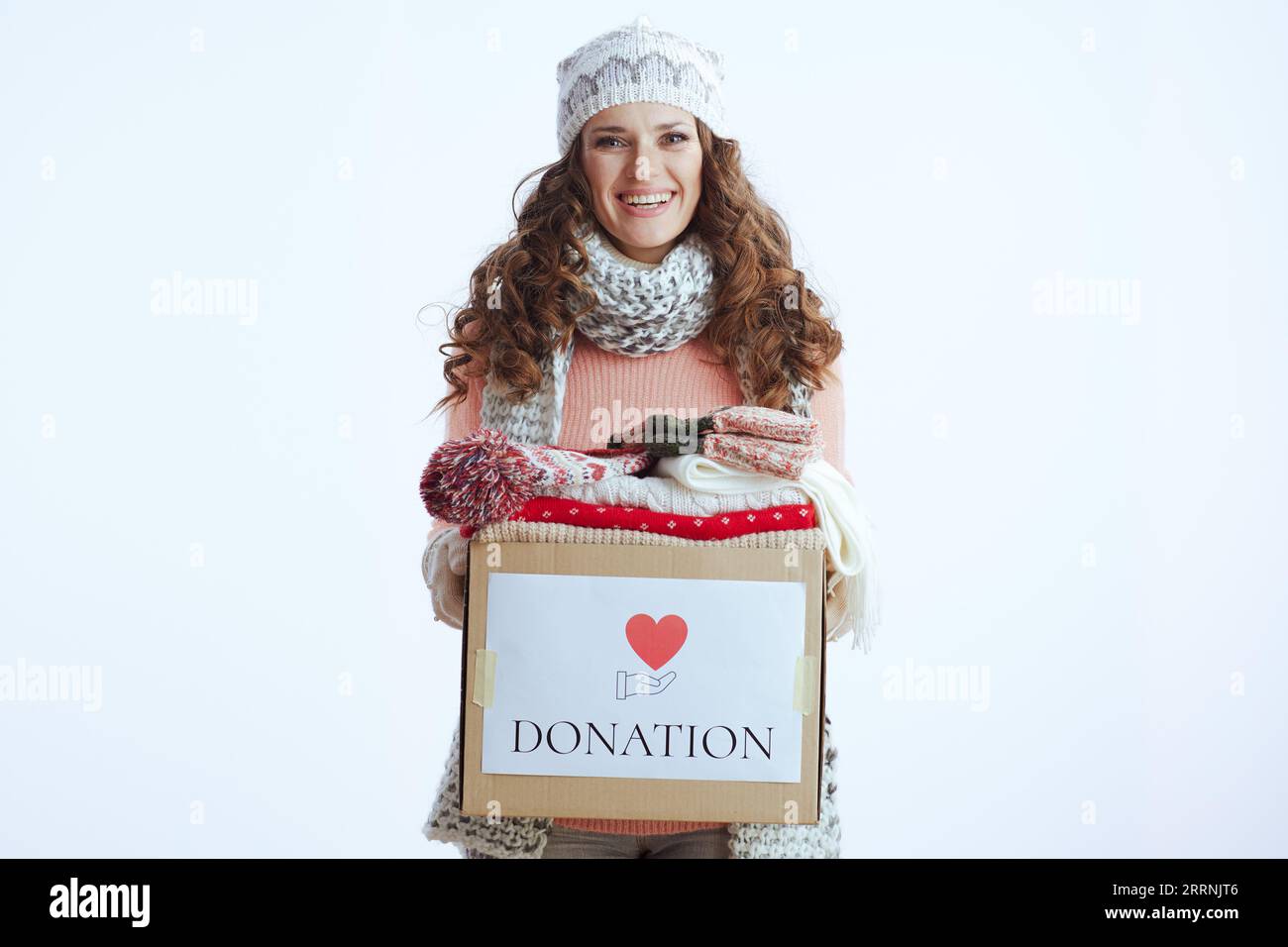 Ciao inverno. elegante donna sorridente di 40 anni con maglione, guanti, cappello e sciarpa con scatola donazione isolata su bianco. Foto Stock
