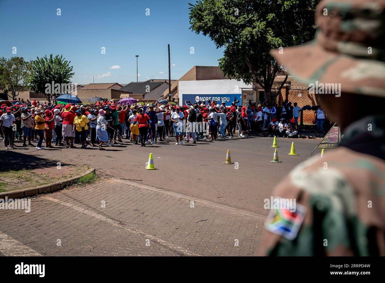 230314 -- GAUTNEG, 14 marzo 2023 -- Un soldato guarda come membri della National Education, Health and Allied Workers Union manifestano fuori da un ospedale a Vosloorus, Gauteng, Sud Africa, 13 marzo 2023. La South African National Defense Force SANDF ha detto lunedì ha schierato medici militari dei servizi sanitari militari sudafricani a seguito dello sciopero dei lavoratori affiliati con il National Education, Health and Allied Workers Union. Foto di Shiraaz Mohamed/Xinhua SUD AFRICA-GAUTNEG-STRIKE ZhangxYudong PUBLICATIONxNOTxINxCHN Foto Stock