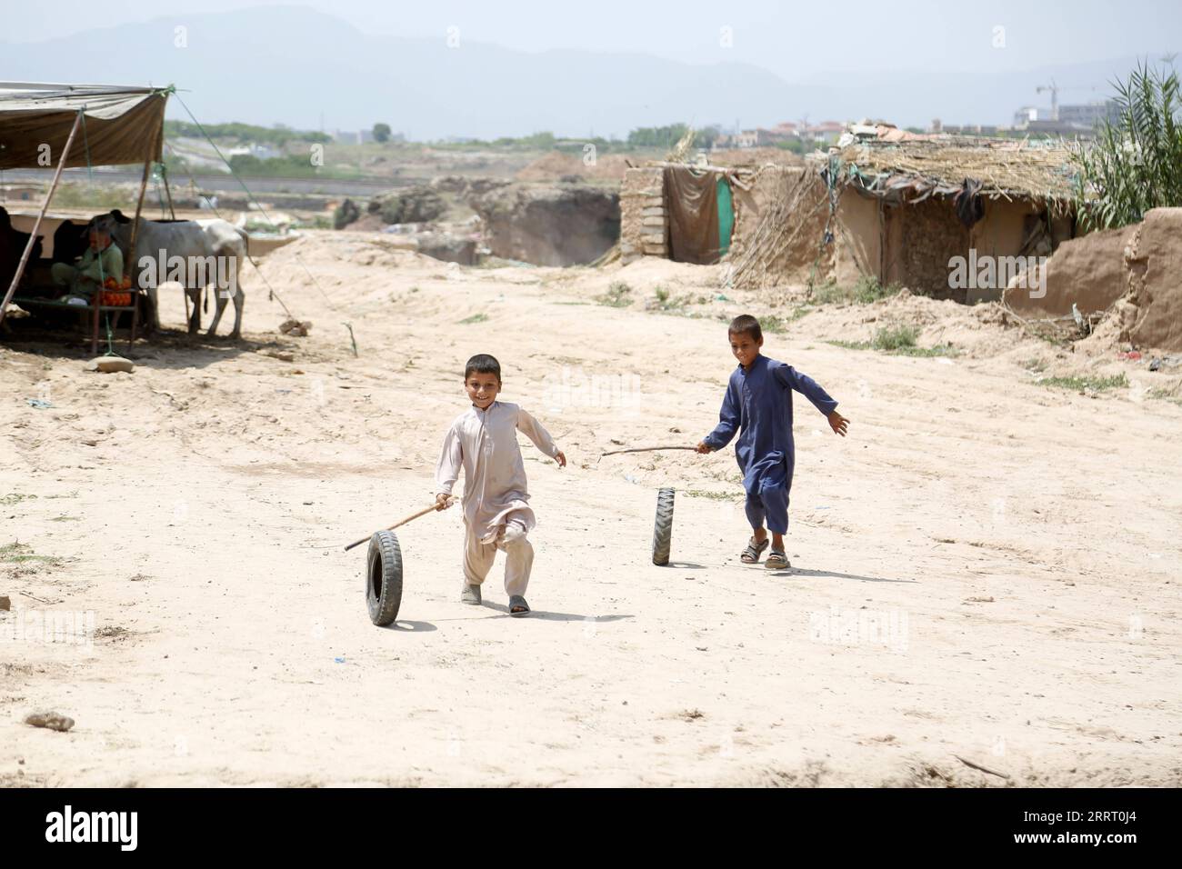 230620 -- ISLAMABAD, 20 giugno 2023 -- i ragazzi giocano con le gomme in un campo profughi nella giornata mondiale dei rifugiati a Islamabad, Pakistan, il 20 giugno 2023. Il presidente pakistano Arif Alvi ha affermato che il suo paese ha continuato ad ospitare una delle più grandi popolazioni di rifugiati al mondo, dimostrando la ferma determinazione e l'impegno del Pakistan per il benessere e il rimpatrio volontario dei rifugiati. Nel suo messaggio in occasione della giornata mondiale dei rifugiati, che è stata celebrata martedì, Alvi ha detto che quel giorno ci vengono ricordati gli immensi contributi del governo e del popolo pakistano nell'ospitare milioni di rifugiati afghani Foto Stock