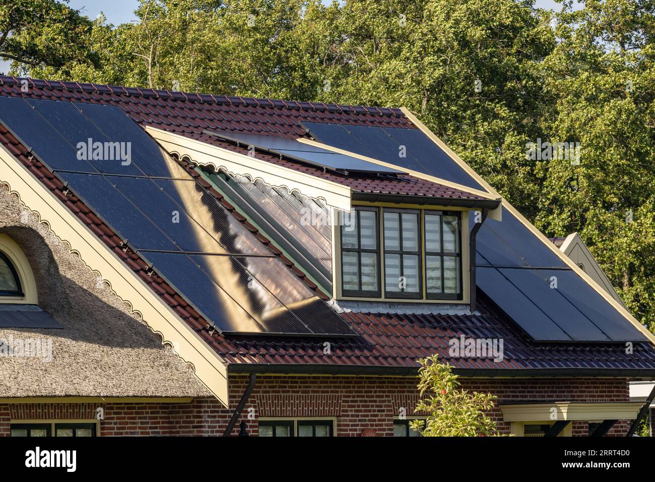 casa indipendente con tetto solare accanto alla casa con tetto in paglia Foto Stock