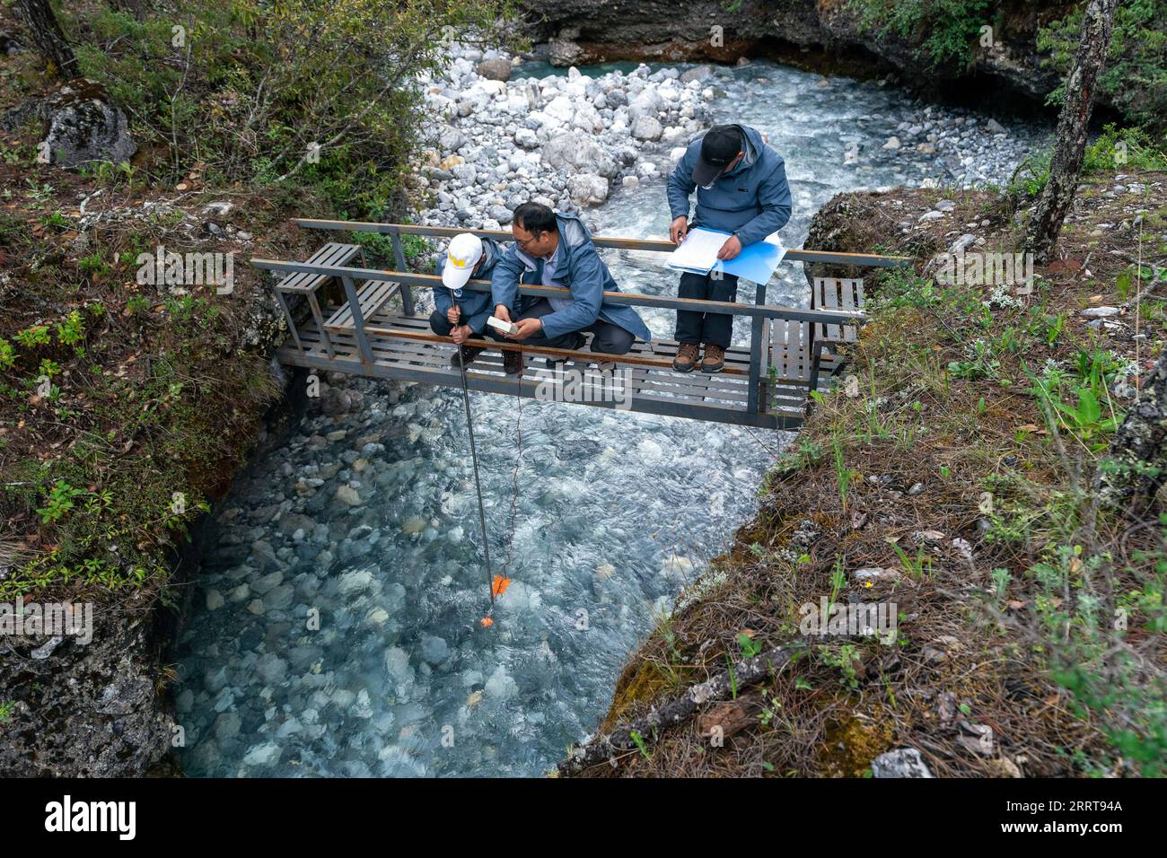 230707 -- LIJIANG, 7 luglio 2023 -- Wang Shijin C misura la velocità del flusso dell'acqua di fusione del ghiacciaio con i suoi compagni di squadra in un punto di osservazione lungo il fiume Baishui nella città di Lijiang, nella provincia dello Yunnan della Cina sud-occidentale, 16 giugno 2023. La Yulong Snow Mountain Cryosphere and Sustainable Development Field Science Observation and Research Station, istituita dal Northwest Institute of Eco-Environment and Resources of Chinese Academy of Sciences, si trova nella città di Lijiang nella provincia dello Yunnan nella Cina sud-occidentale. Dal 2006, i ricercatori hanno regolarmente monitorato le condizioni del ghiacciaio n. 1 del fiume Baishui e. Foto Stock