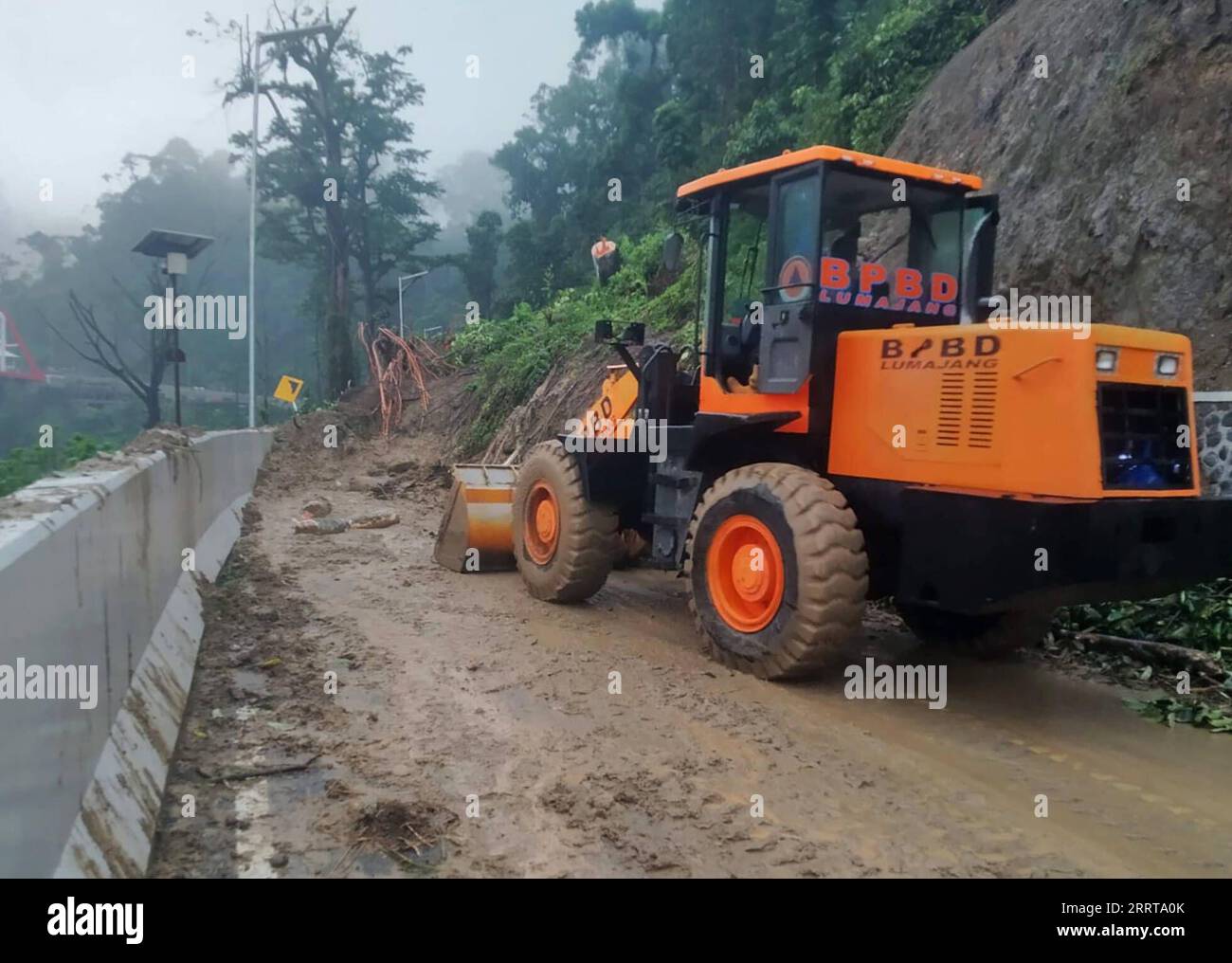 230708 -- LUMAJANG, 8 luglio 2023 -- questa foto fornita dalla National Disaster Management Agency dell'Indonesia mostra un ufficiale che gestisce un escavatore per pulire un sito di frana nel villaggio di Sumberwuluh, reggenza di Lumajang, Giava Orientale, Indonesia, 8 luglio, 2023. tre persone sono morte e alcune strade sono state chiuse in frane nella reggenza di Lumajang, nella provincia di Giava Orientale in Indonesia, venerdì. Le autorità hanno utilizzato escavatori per riaprire le strade chiuse, ma la risposta di emergenza ha dovuto essere temporaneamente interrotta a causa delle successive frane. /Handout via Xinhua INDONESIA-LUMAJANG-LANDSLIDE-AFTERMATH BNPB PUBLICAT Foto Stock