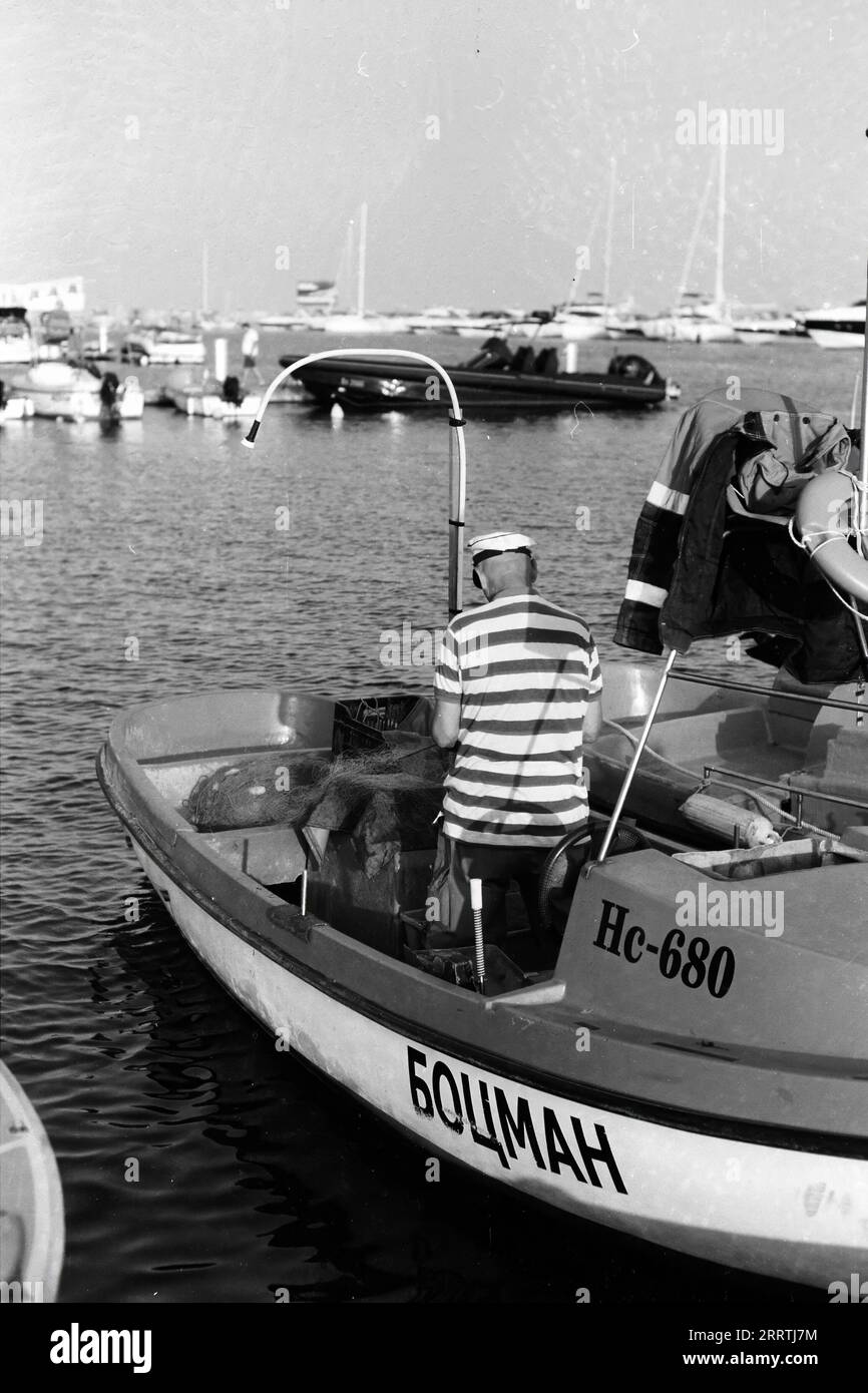Fotografia di un pescatore tradizionale in una piccola barca al porto di Sveti Vlas, ripresa su pellicola in bianco e nero Foto Stock