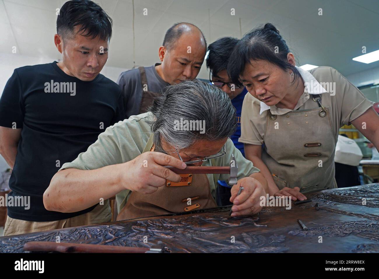 230815 -- NANCHANG, 15 agosto 2023 -- Huang Junjun mostra abilità di incisione del rame ai suoi apprendisti in un laboratorio della sua azienda nella città di Guixi, nella provincia del Jiangxi della Cina orientale, 13 luglio 2023. L'incisione in rame, o intaglio in rame, un mestiere di uso di coltelli per intagliare modelli su ceramiche in rame, ha una storia di circa 1.000 anni. Nel 2021, l'incisione del rame Guixi è stata elencata come uno dei patrimoni culturali immateriali a livello nazionale. L'artigianato ha bisogno di oltre 150 tipi diversi di coltelli e una dozzina di abilità di intaglio per creare un'opera d'arte completa, e la ceramica di rame deve attraversare oltre 100.000 volte di ettaro Foto Stock