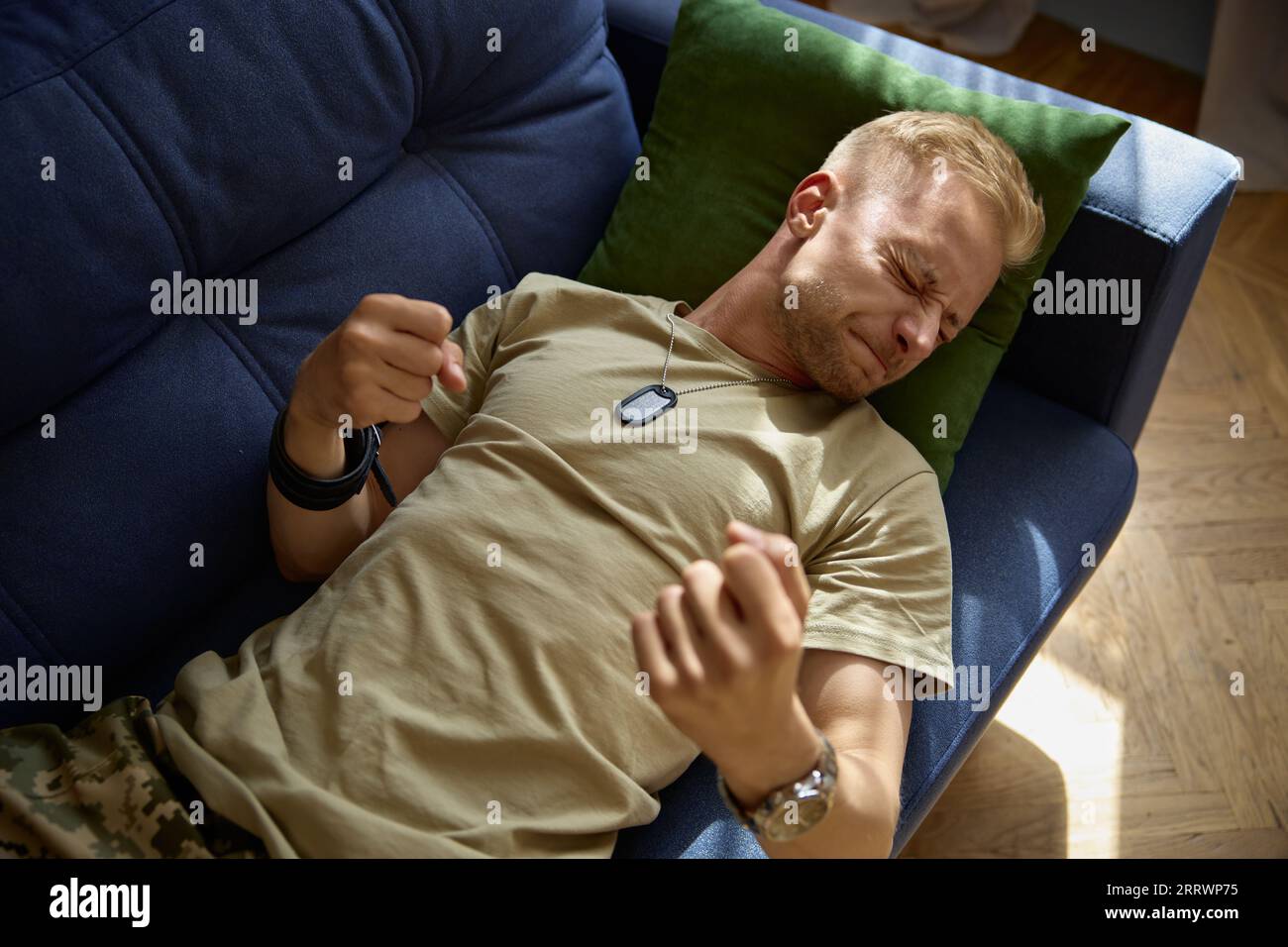 L'uomo militare che si inghiottisce la faccia sdraiata sul divano abbattendo la disperazione persa Foto Stock