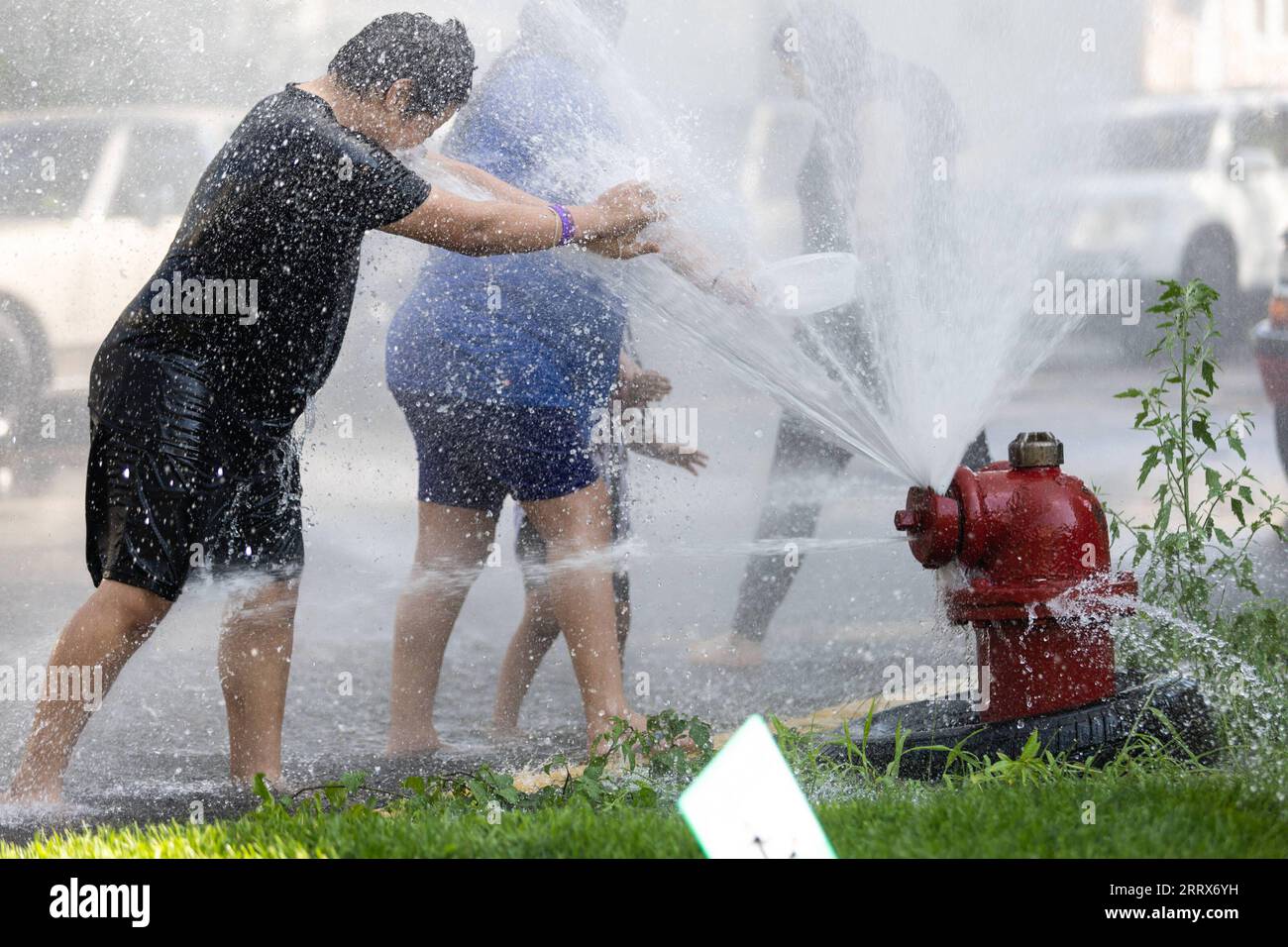 230824 -- CHICAGO, 24 agosto 2023 -- bambini e adulti si raffreddano accanto a un idrante di fuoco aperto nel quartiere di New City nel lato sud-ovest di Chicago, negli Stati Uniti, il 23 agosto 2023. La temperatura dell'aeroporto internazionale o Hare di Chicago, la terza città più popolosa degli Stati Uniti, ha raggiunto i 98 gradi Fahrenheit 36,67 gradi Celsius mercoledì pomeriggio, superando il precedente record giornaliero di alta temperatura della città per il 23 agosto su 97 gradi Fahrenheit 36,11 gradi Celsius, secondo il National Weather Service degli Stati Uniti. Il precedente record per il 23 agosto fu stabilito nel 1947, Chicago Sun Foto Stock