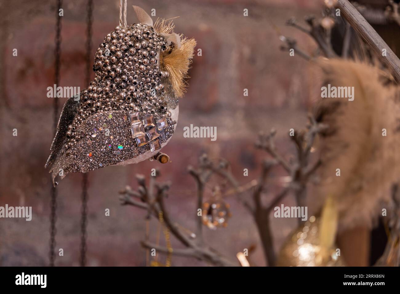 Un uccello scintillante ornamento artificiale dell'albero di Natale catturato dalla profondità di campo. L'uccello artificiale è isolato contro il muro come sfondo. Foto Stock