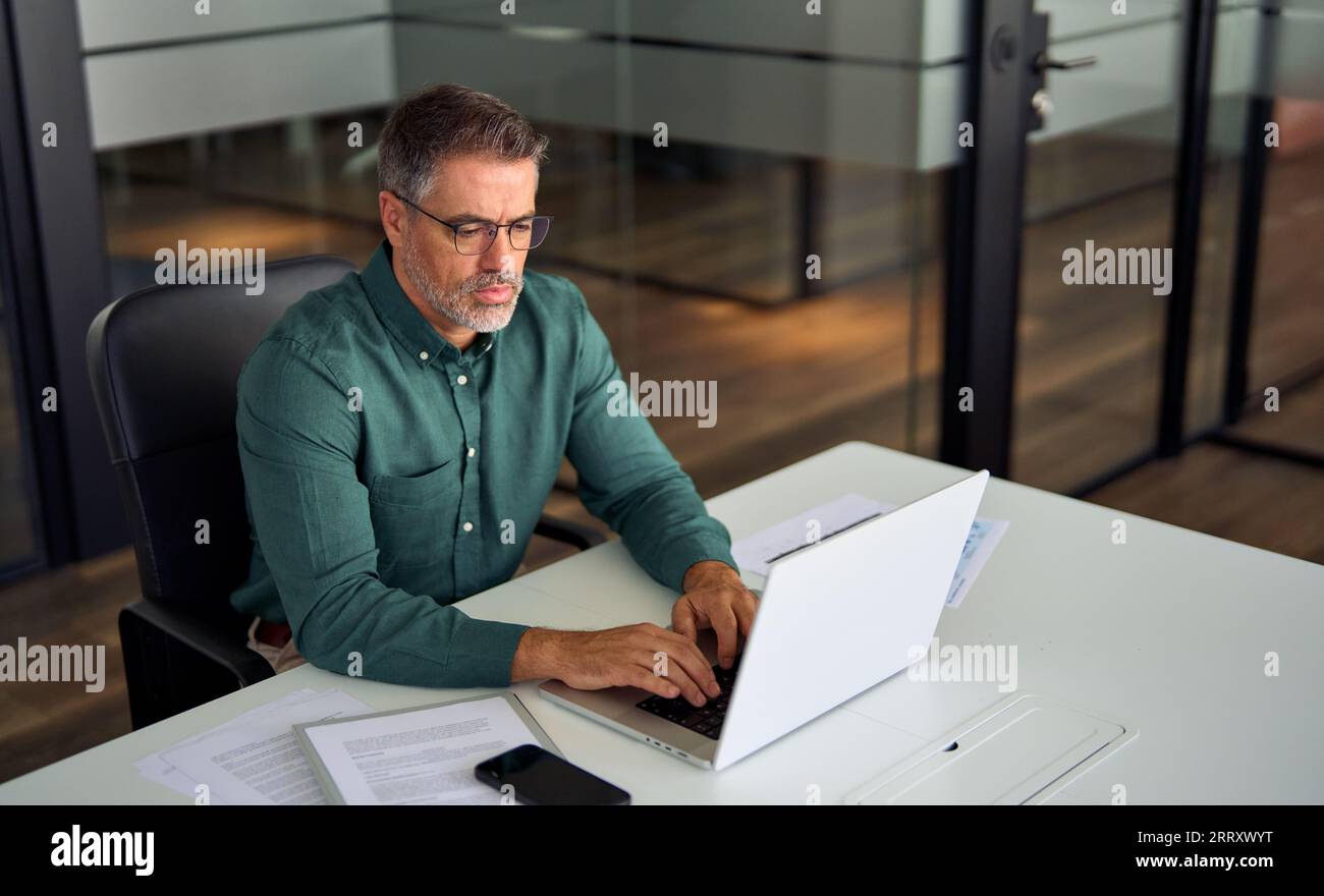 Un uomo d'affari professionista di mezza età che lavora con un computer portatile alla scrivania. Foto Stock