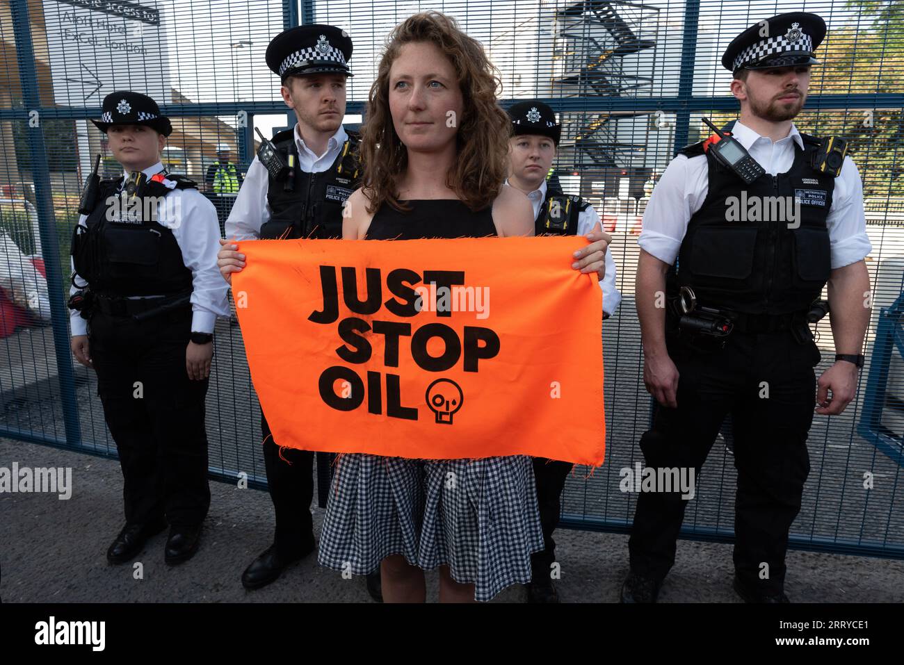 Londra, Regno Unito. 9 settembre 2023. Una donna si trova ai cancelli del centro Excel con un banner Just Stop Oil mentre gli attivisti anti-guerra protestano e tentano di bloccare la mostra sulle armi DSEI (Defence & Security Equipment International) che aprirà la prossima settimana. La fiera, una delle più grandi al mondo, si svolge dal 12 al 15 settembre e, dicono gli attivisti, attira clienti da regimi repressivi che cercano di acquistare di tutto, dalle apparecchiature di sorveglianza alle navi da guerra. Anche l'esercito mondiale è uno dei principali emettitori di CO2 responsabili del riscaldamento globale. Crediti: Ron Fassbender/Alamy Live News Foto Stock