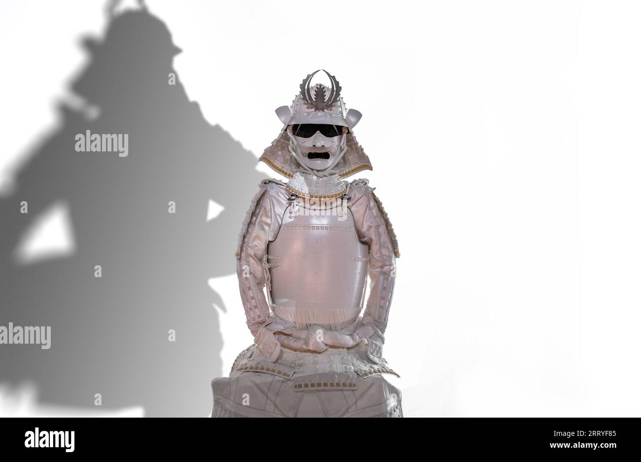 Ritaglio isolato di un'armatura kachuu giapponese seduta dipinto di bianco con un casco Kabuto e un'armatura yoroi su sfondo bianco con un kagemusha shado Foto Stock