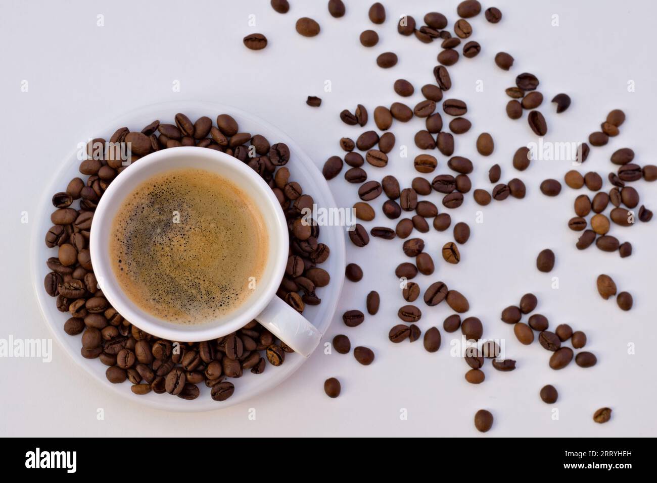 Tazza di caffè nero e piattino con chicchi di caffè su sfondo bianco. Foto Stock