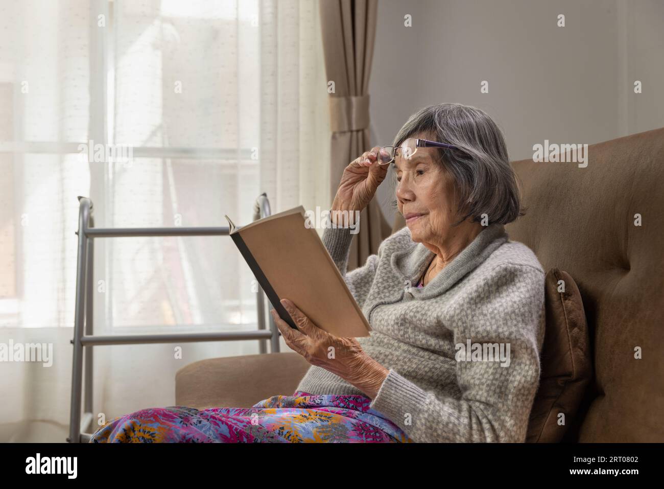 La donna anziana asiatica sta leggendo un libro per rilassarsi a casa di cura. Foto Stock