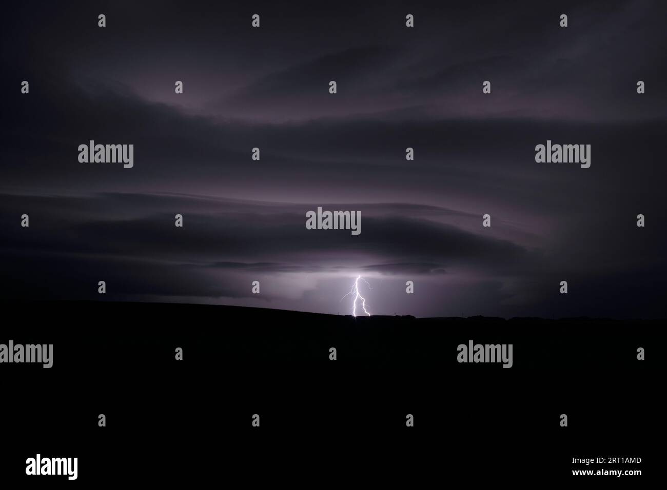 Fulmini a distanza che illuminano le formazioni di nubi surreali del sistema di tempeste meteorologiche in Alberta, Canada. Foto Stock