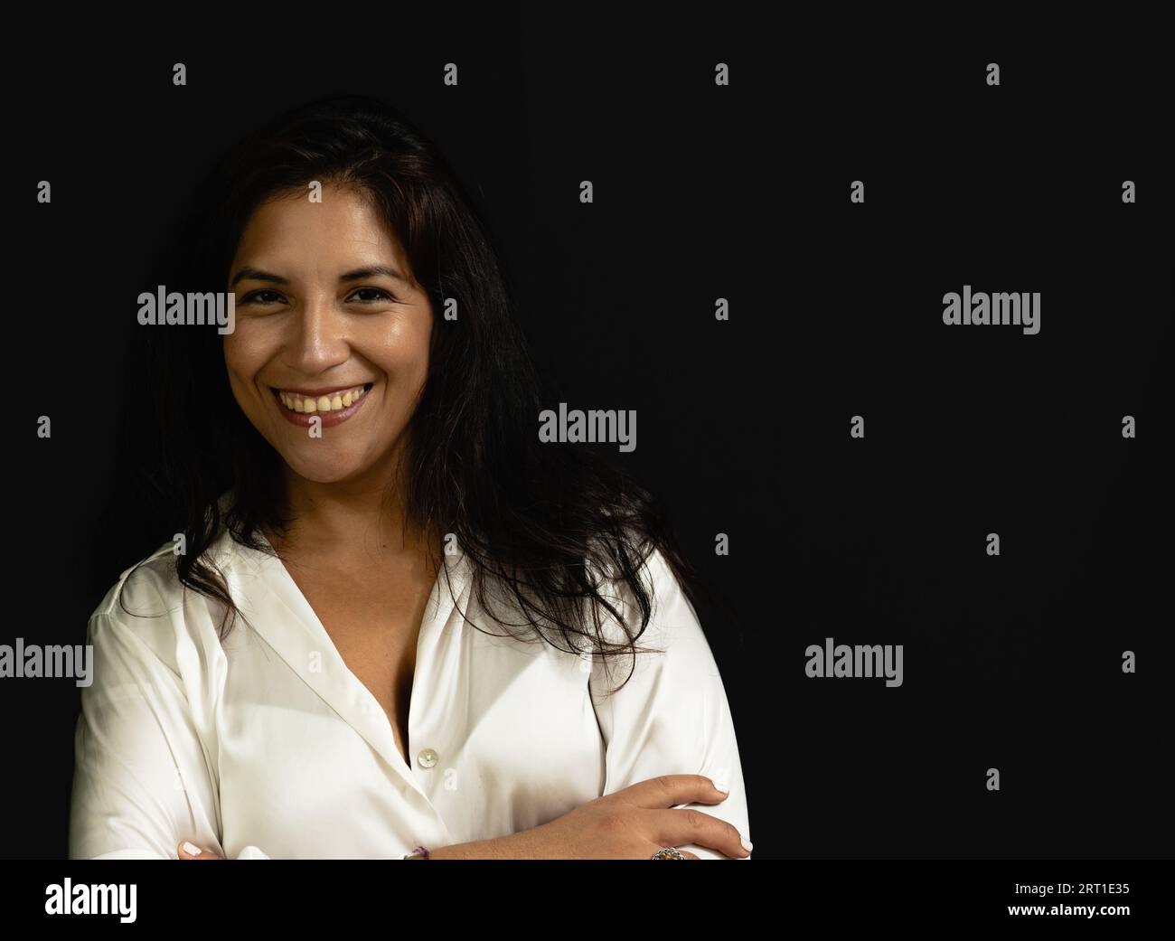 segretaria donna latina con camicia bianca e sfondo nero sorridente Foto Stock