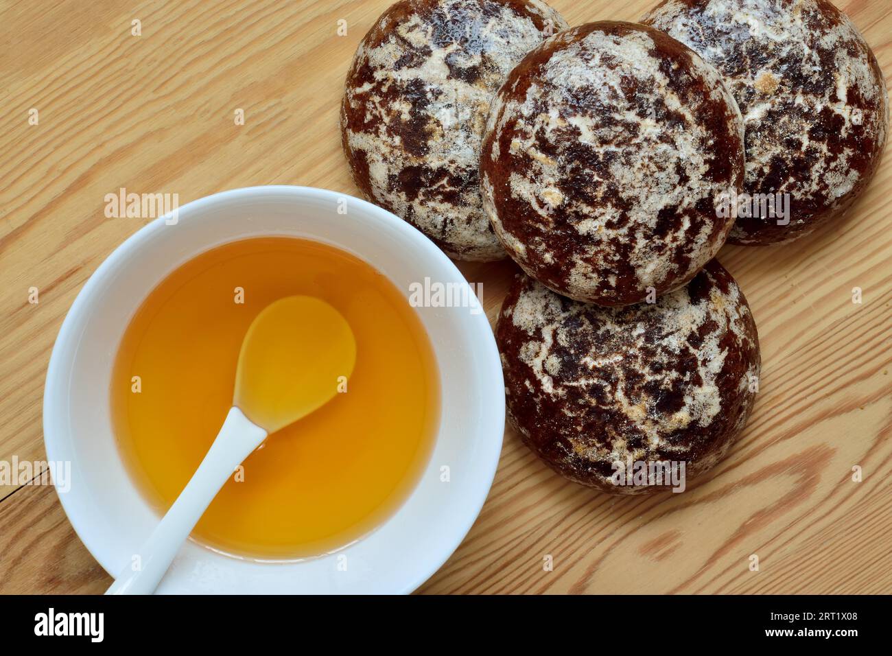 Miele in una tazza bianca e pan di zenzero al cioccolato su un primo piano su sfondo in legno Foto Stock