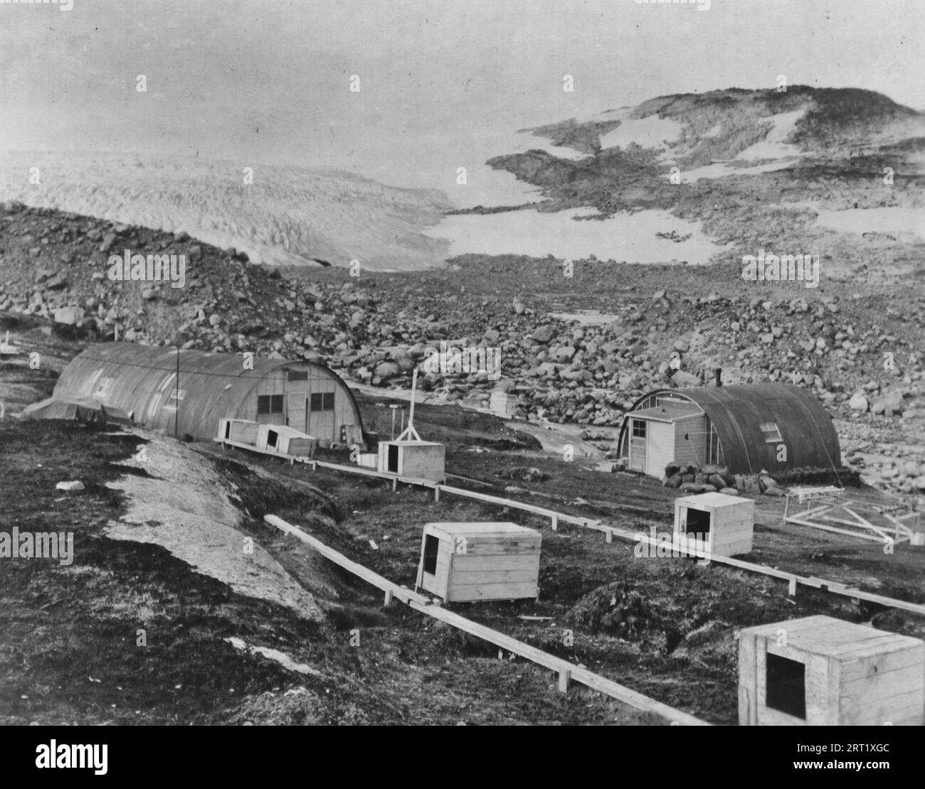 Vista di Cape Adelaer, Groenlandia. Il magazzino sulla sinistra e sulla destra è Rescue House of 1943-1944 Bicd Installation. In primo piano si possono vedere Doghouses. Water for Camp è normalmente ottenuto da ruscello che corre a destra di Rescue House - 1947 Foto Stock