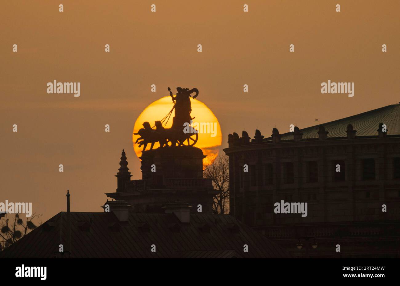 Tramonto a Dresda. Il disco del sole, in particolare arancione a causa della polvere del Sahara, tramonta dietro la quadriga sul portale del Semper Opera House Foto Stock