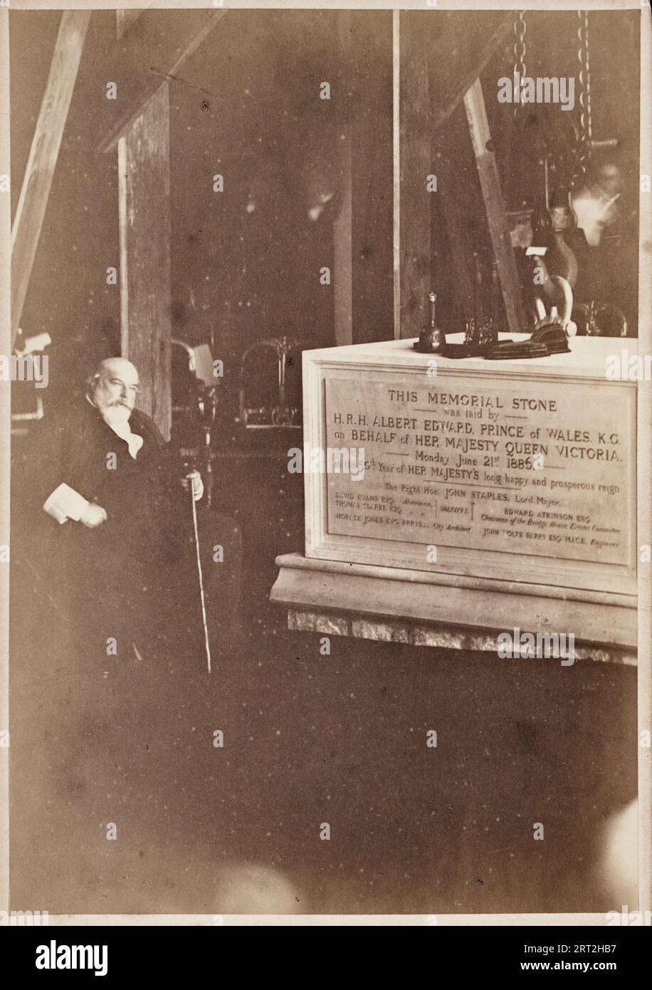 Tower Bridge, Tower Hamlets, Greater London Authority, giugno 1886. Un ritratto di Sir Horace Jones seduto accanto alla prima pietra del Tower Bridge. Sir Horace Jones (1819-1887) fu l'architetto del Tower Bridge, che progettò in collaborazione con l'ingegnere civile John Wolfe Barry. Questa scheda di gabinetto lo mostra seduto, attaccato in mano, accanto alla prima pietra del ponte intorno alla quale è possibile vedere il blocco e l'attacco utilizzati per manovrare la pietra nel suo luogo di riposo sul lato sud del Tamigi. La fotografia è stata presumibilmente scattata in un tendone temporaneo eretto per ospitare il sto Foto Stock