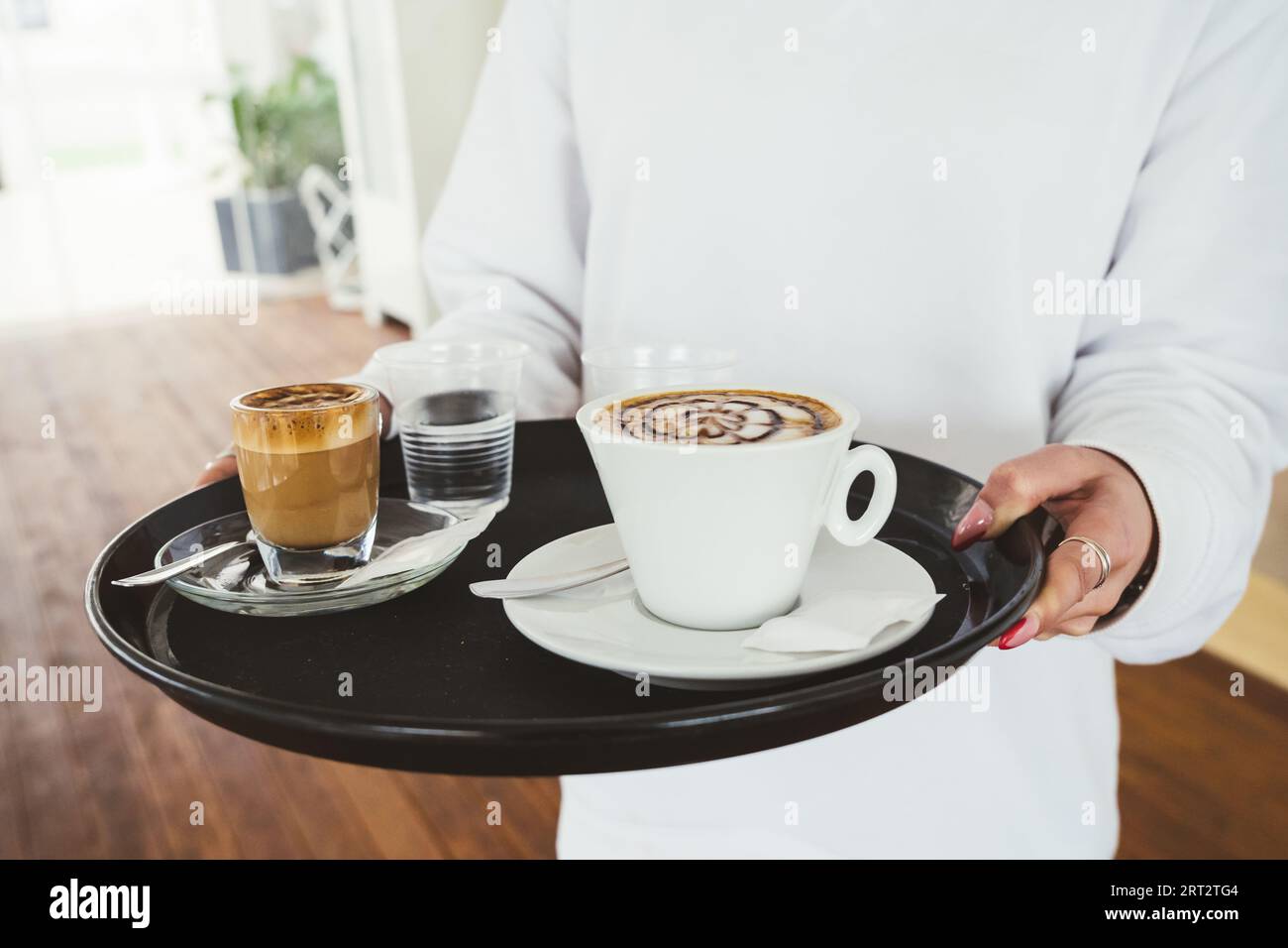 cameriera irriconoscibile che tiene un vassoio per la colazione in una caffetteria Foto Stock