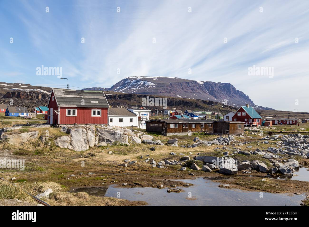 Qeqertarsuaq, Groenlandia, 4 luglio 2018: Una strada con case di legno colorate con montagne basaltiche con sommità piatta sullo sfondo Foto Stock